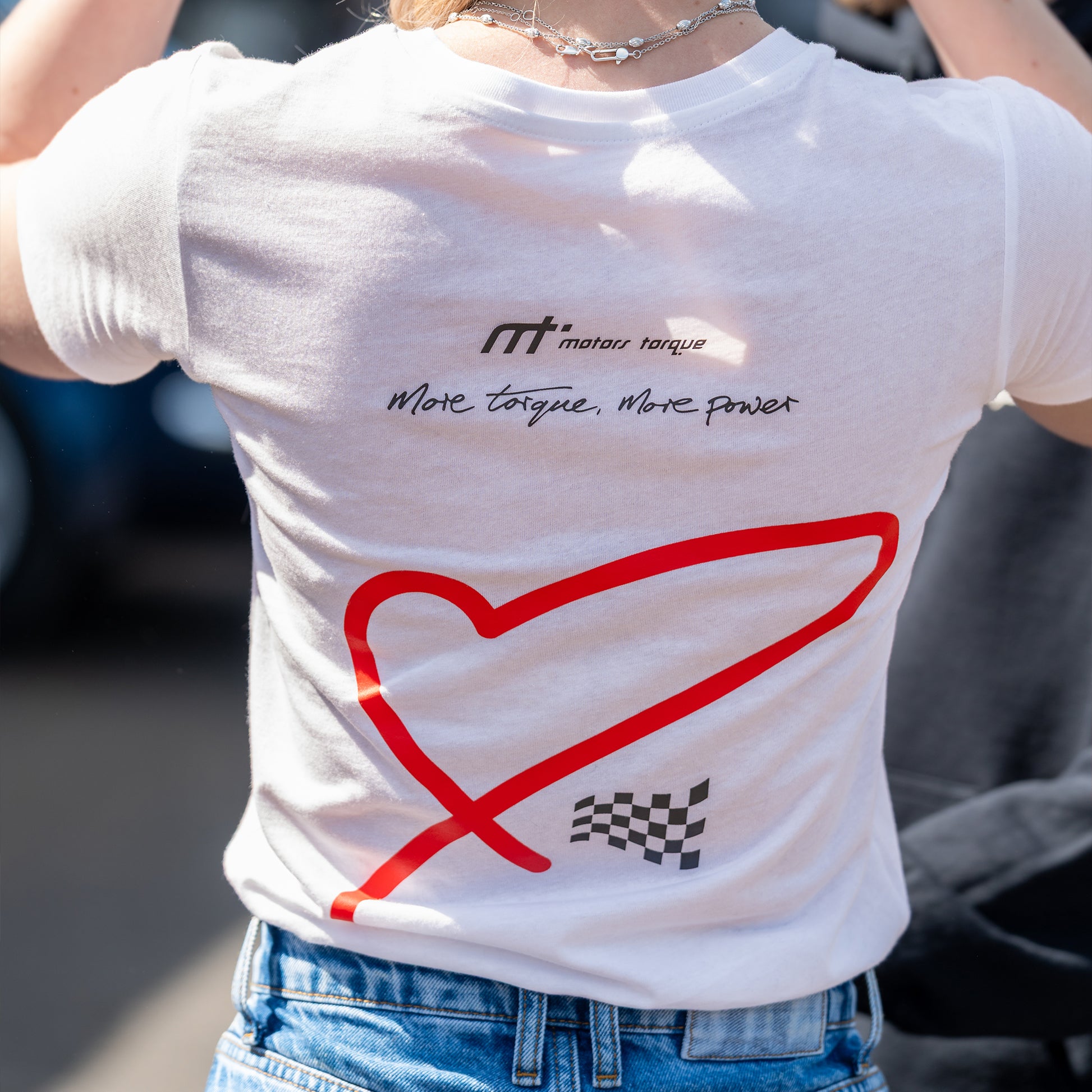 This ‘T’ is the cam of our collection. Featuring our MT brand on the front with for the love of heart and flag, with a larger heart and flag motif on the back. This ‘T’ was designed to convey the love of motorsport.

Why white? It’s a stylish backdrop for the red heart and chequered flag and cooler in the sun. This ‘T’ is inspired by a love of motorsport and is a great tribute to the thrill of the race.

Our t-shirts are soft and durable just like our community.

This ‘T’ is a ladies more snug fit (this run